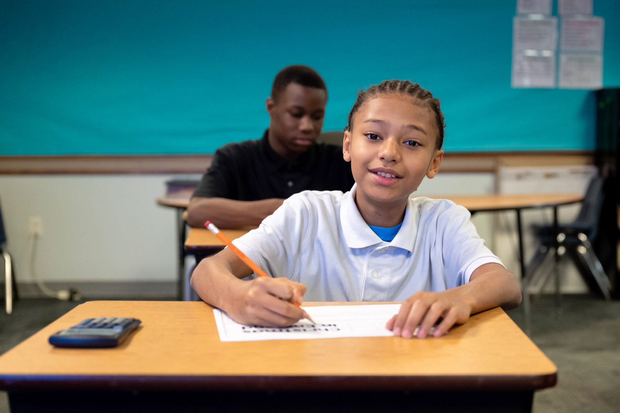 Student writing at desk